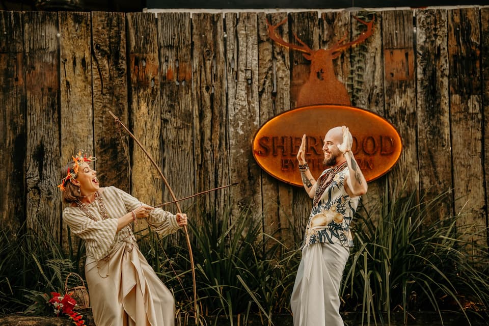 A couple sharing a joyful moment beside the Sherwood by The Barn sign, surrounded by greenery
