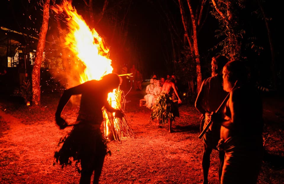 Ceremonial fire glowing at night as guests gather for stories and music