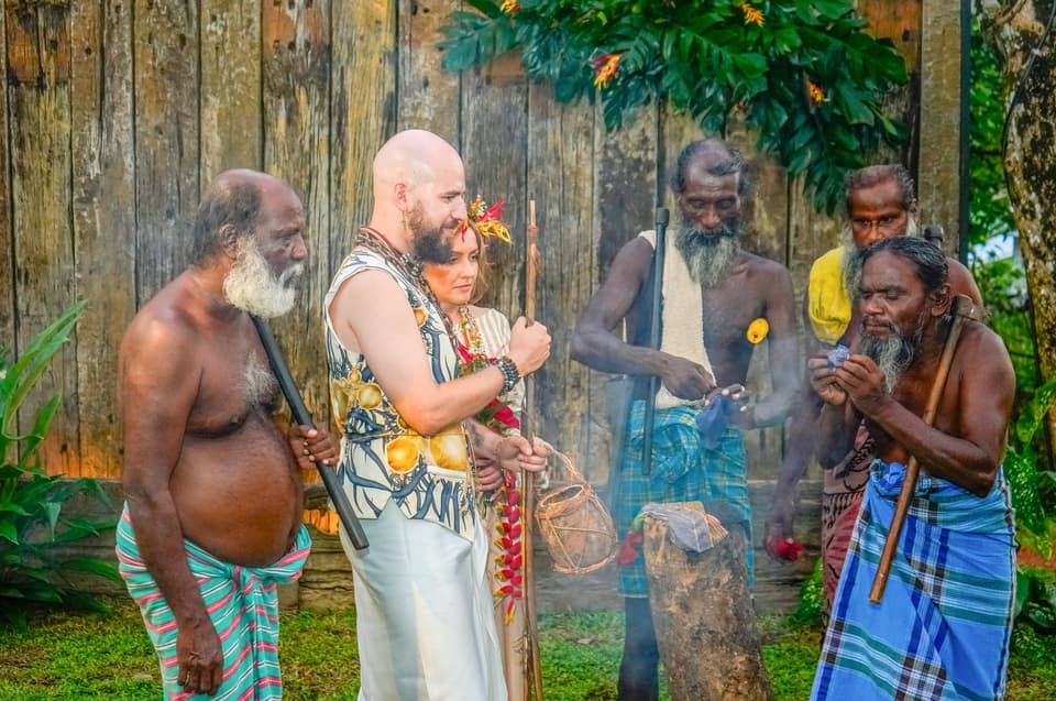 Elders kindling a smoking ceremonial fire beside the couple in traditional dress