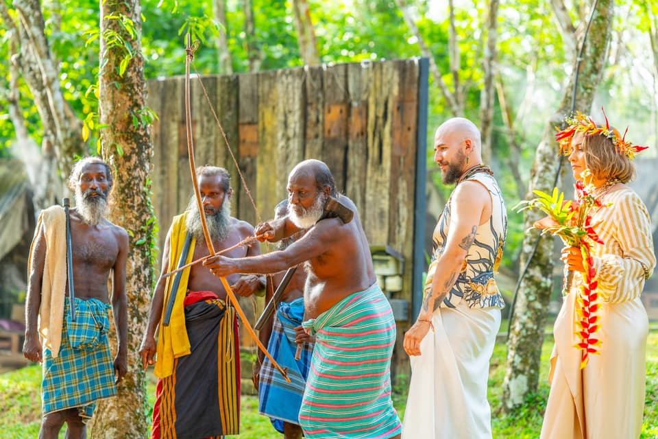 Vedda community elders demonstrating a traditional bow beneath the forest canopy